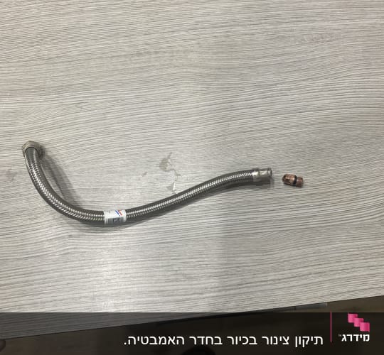 צינור גמיש ומחבר מתכת על שולחן